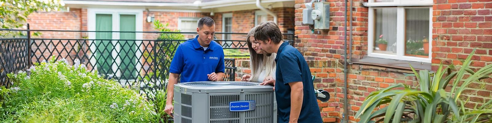 HVAC Technician with Homeowners at an Outdoor Unit