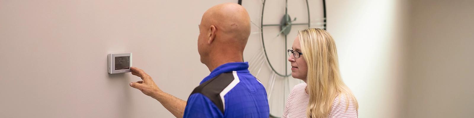Homeowner and HVAC Technician in Front of an American Standard Smart Thermostat